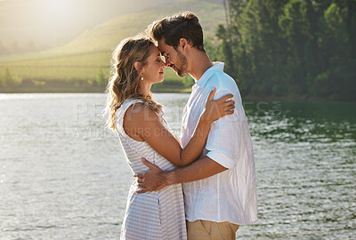 Buy stock photo Couple, head touch and hug by lake for outdoor date, romantic adventure and summer love in nature. Man, woman and romance with embrace, care and bond by water with sunshine, freedom and happiness