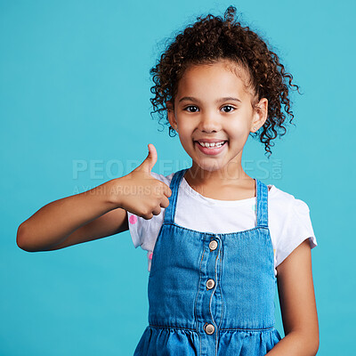 Buy stock photo Happy, portrait and girl child with thumbs up in a studio with success, happiness and achievement. Smile, positive and face of a kid with a satisfaction or approval hand gesture by a blue background.