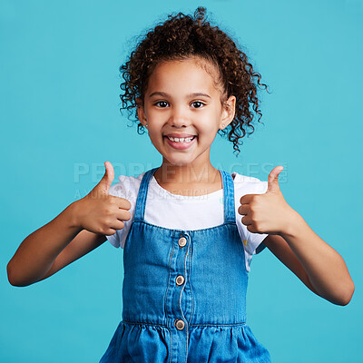 Buy stock photo Smile thumbs up and portrait of a kid in a studio with success, happiness and achievement. Happy, positive and face of a girl child with a satisfaction or approval hand gesture by a blue background.