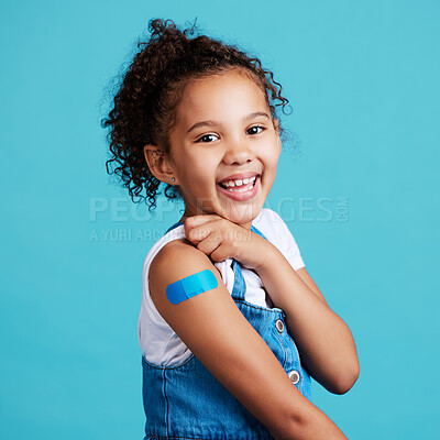 Buy stock photo Portrait, smile and girl with plaster, wellness and safety with kid against a blue studio background. Face, young person and female child with happiness, band aid and vaccine with protection and care