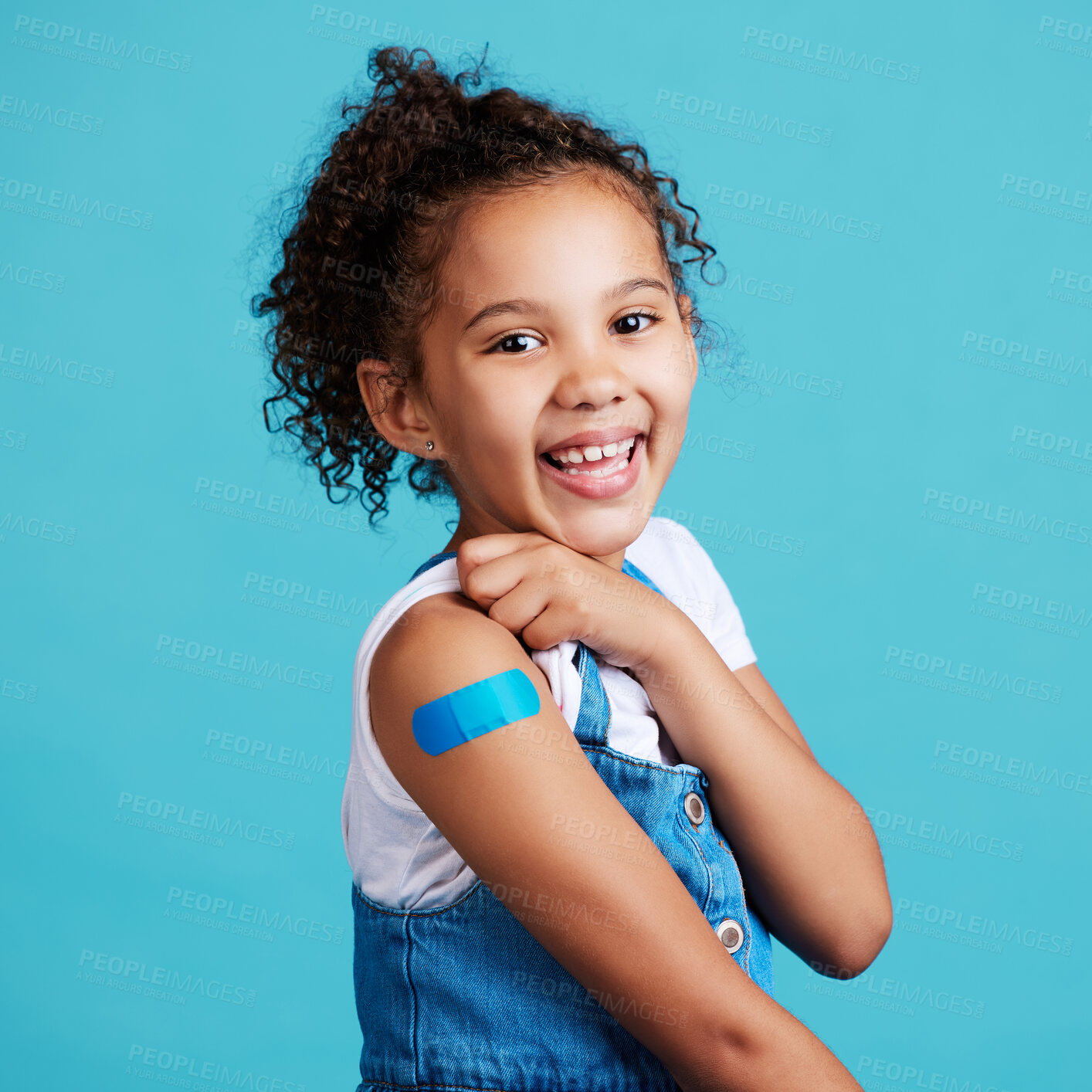 Buy stock photo Portrait, smile and girl with plaster, wellness and safety with kid against a blue studio background. Face, young person and female child with happiness, band aid and vaccine with protection and care