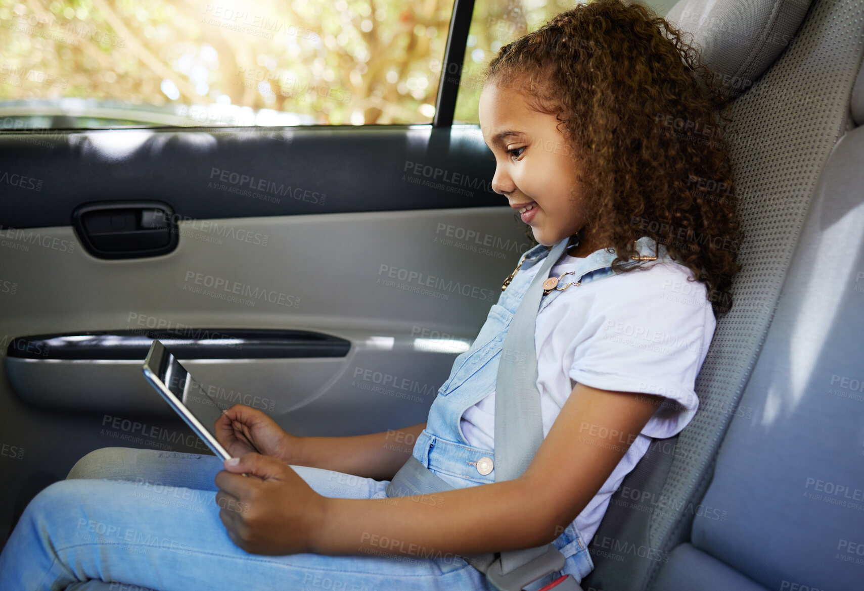 Buy stock photo Happy, road trip and a child in a car with a tablet for a movie, cartoons or video. Smile, travel and a girl sitting in a vehicle with tech, streaming online and enjoying a film for entertainment