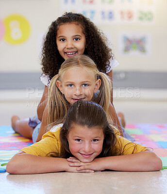 Buy stock photo School kids, lying together and pile on floor, portrait and classroom for smile, solidarity or diversity. Girl, children and class at academy, happy or multicultural friends with support for learning