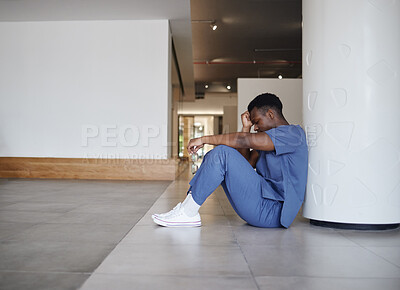 Buy stock photo Shot of a young male doctor looking tired while working in a modern hospital