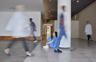 Buy stock photo Shot of a young female doctor looking tired while working in a busy hospital