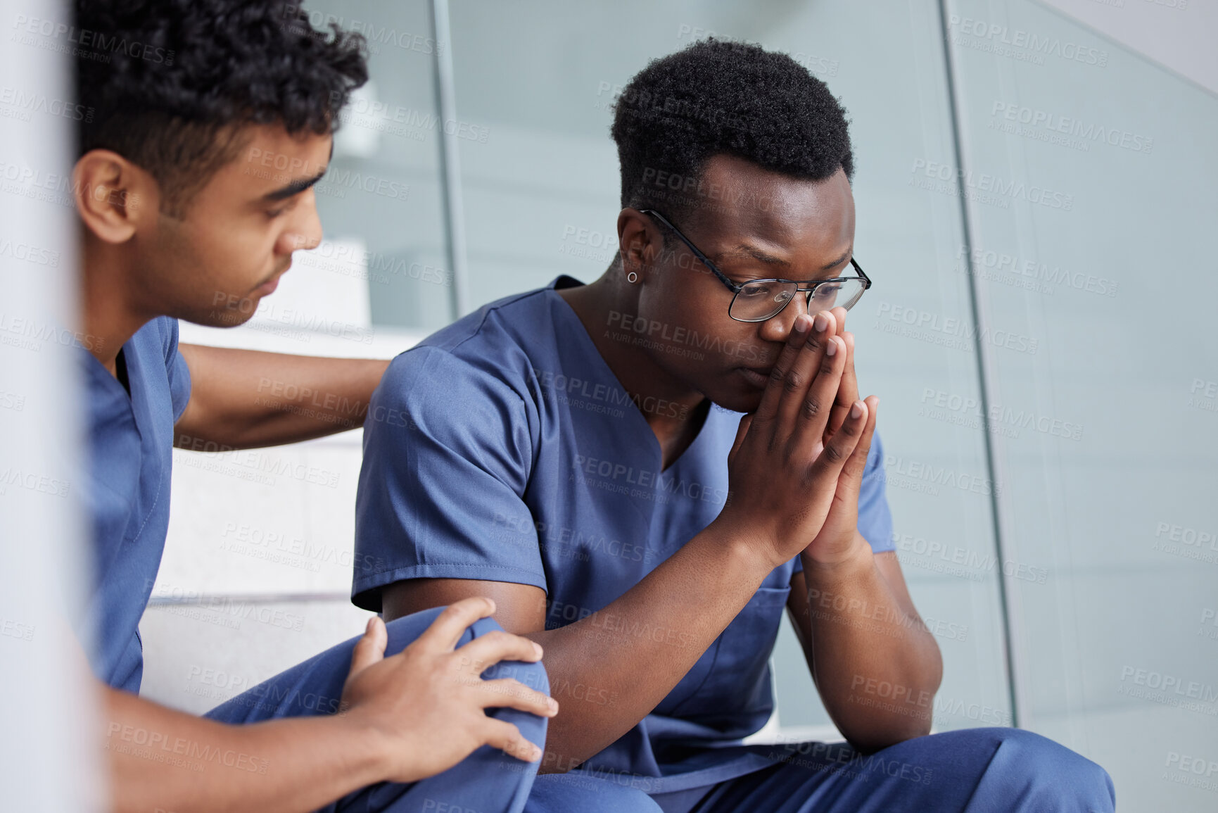 Buy stock photo Shot of a young male doctor consoling a coworker at work