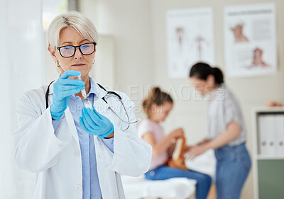 Buy stock photo Shot of a mature female doctor preparing a vaccine at a hospital