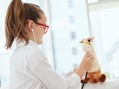 Buy stock photo Shot of a little girl pretending to be a doctor while examining her stuffed animal at home