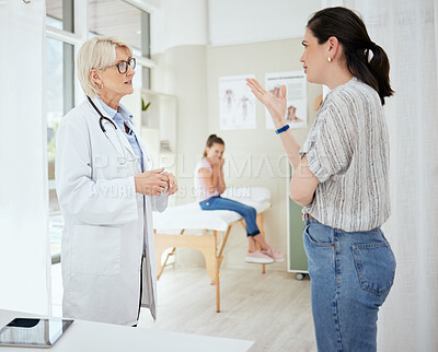 Buy stock photo Shot of a mature female doctor talking to a patient's mother at a hospital