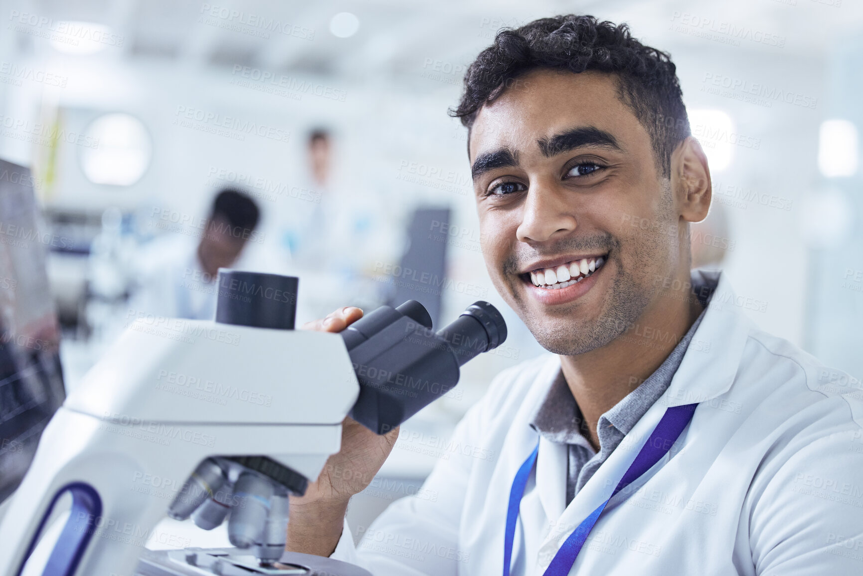 Buy stock photo Shot of a young male lab technician using a microscope