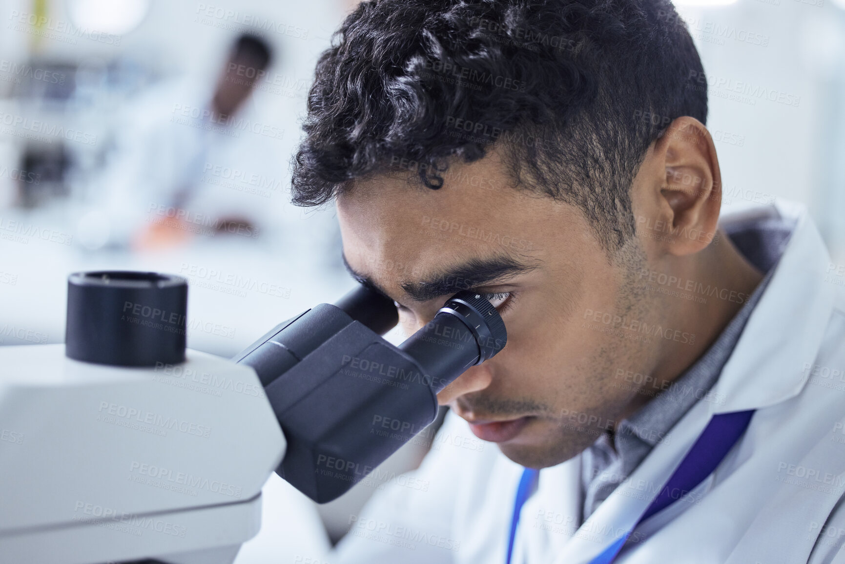 Buy stock photo Shot of a young male lab technician using a microscope