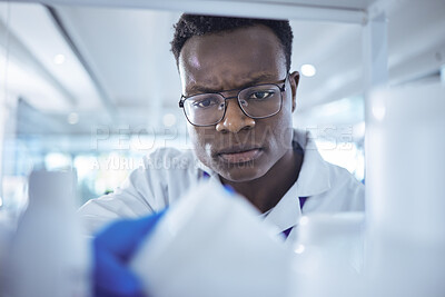Buy stock photo Shot of a young male scientist looking for a product in his lab