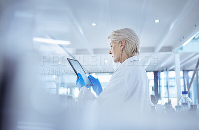 Buy stock photo Shot of a mature female scientist using a digital tablet in her lab