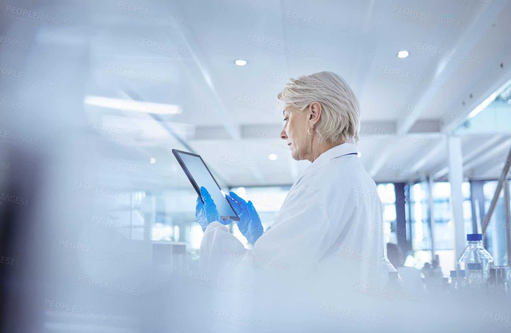 Buy stock photo Shot of a mature female scientist using a digital tablet in her lab