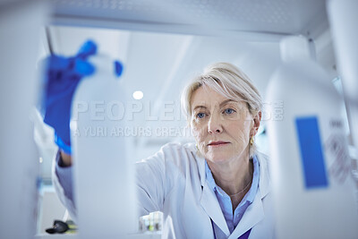 Buy stock photo Shot of a mature female scientist searching for a product in her lab