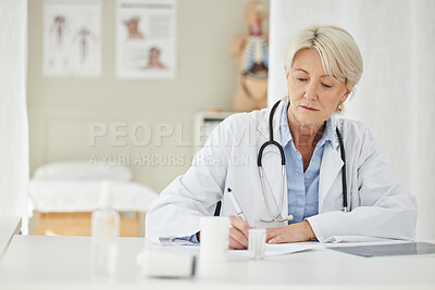Buy stock photo Shot of a mature doctor filling out prescriptions in her office
