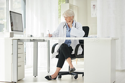 Buy stock photo Shot of a mature doctor filling out prescriptions in her office