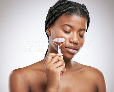 Buy stock photo Beauty, skincare and face roller with black woman in studio for cosmetics, collagen and facial. Self care, glow and shine with model on white background for clean, lymphatic drainage and massage