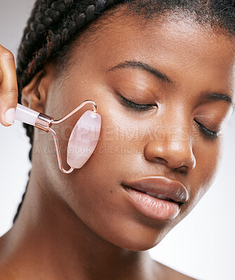 Buy stock photo Glow, skincare and face roller with black woman in studio for cosmetics, collagen and facial. Self care, clean and shine with model on white background for beauty, lymphatic drainage and massage