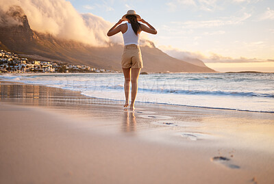 Buy stock photo Rearview shot of a woman taking a walk along the beach