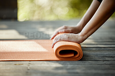 Buy stock photo Closeup shot of an unrecognizable young female athlete rolling out her yoga mat outdoors