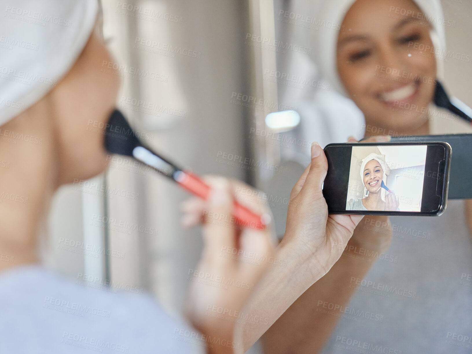 Buy stock photo Shot of a young woman recording herself applying makeup at home