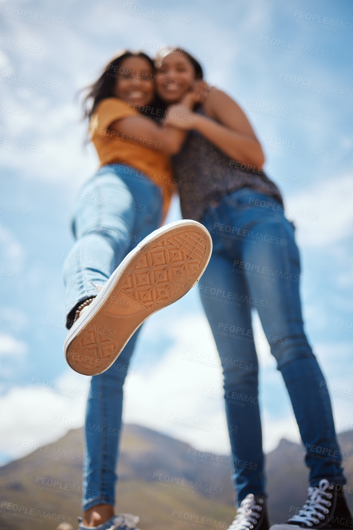 Buy stock photo Low angle, woman and hug with blue sky on holiday for outdoor adventure, weekend and bonding. Happy, foot and friends with clouds in nature for summer on vacation and tourism together