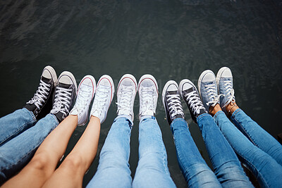 Buy stock photo Above, people and sneakers at water for relax, journey break and comfort on harbor. Friends, feet or rest on dock for summer vacation, student holiday or enjoy sunshine on pier for social gathering