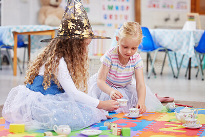 Buy stock photo Girl, friends and tea party with play in classroom for witch costume, hat or learning on floor. Children, magic and help for social development, growth or game with toys, fun or cups at kindergarten