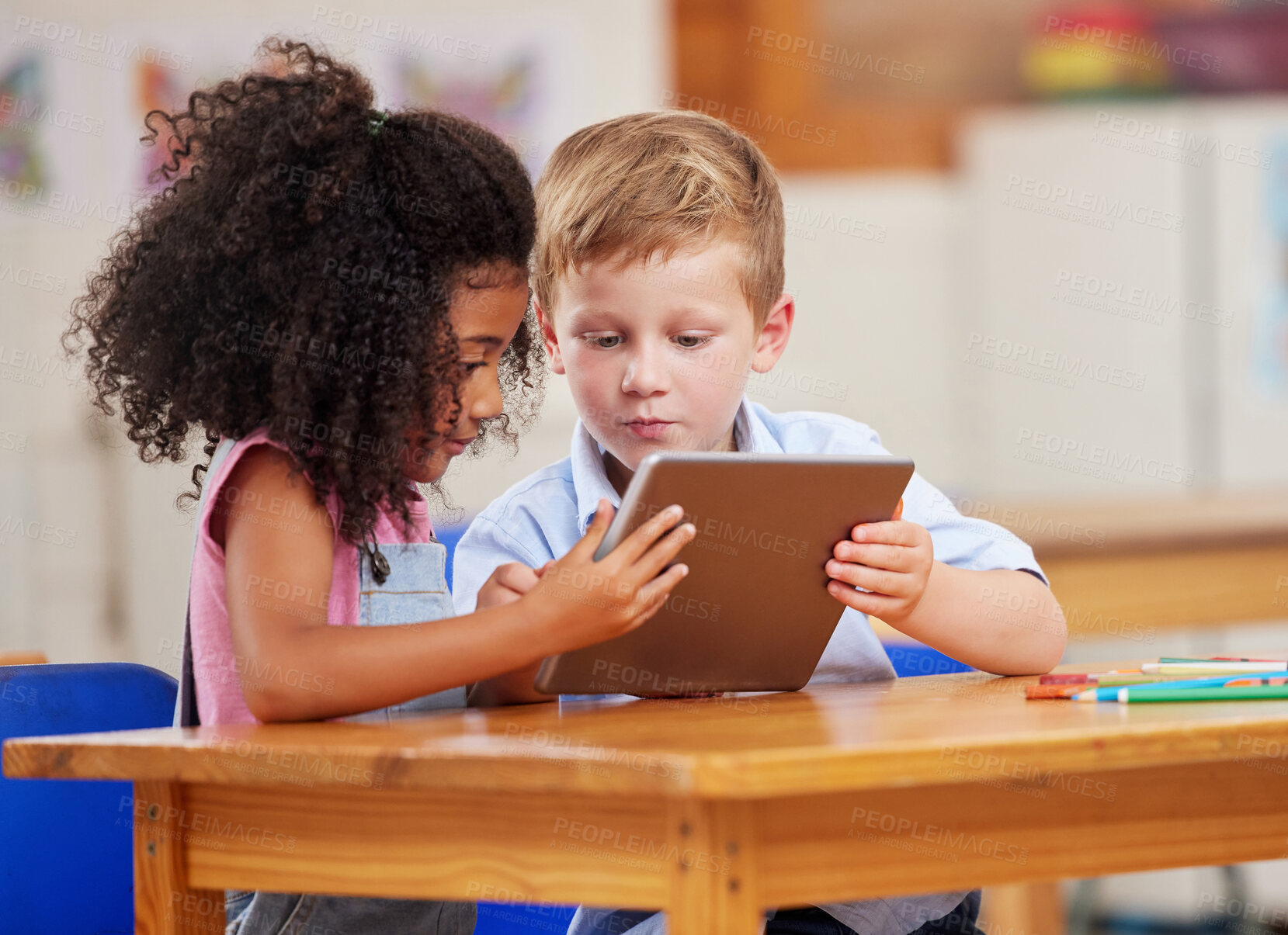 Buy stock photo Shot of two preschool students looking at something on a digital tablet together