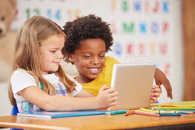 Buy stock photo Shot of two preschool students looking at something on a digital tablet together