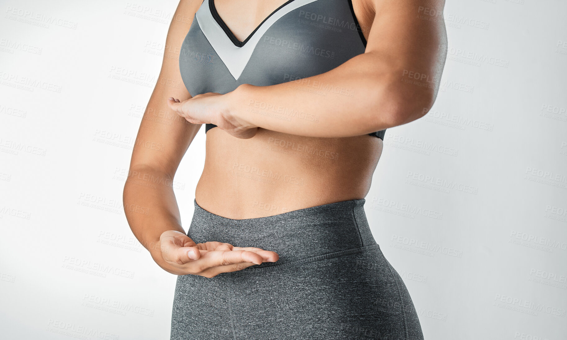 Buy stock photo Studio shot of an unrecognisable woman framing her stomach with her hands against a grey background