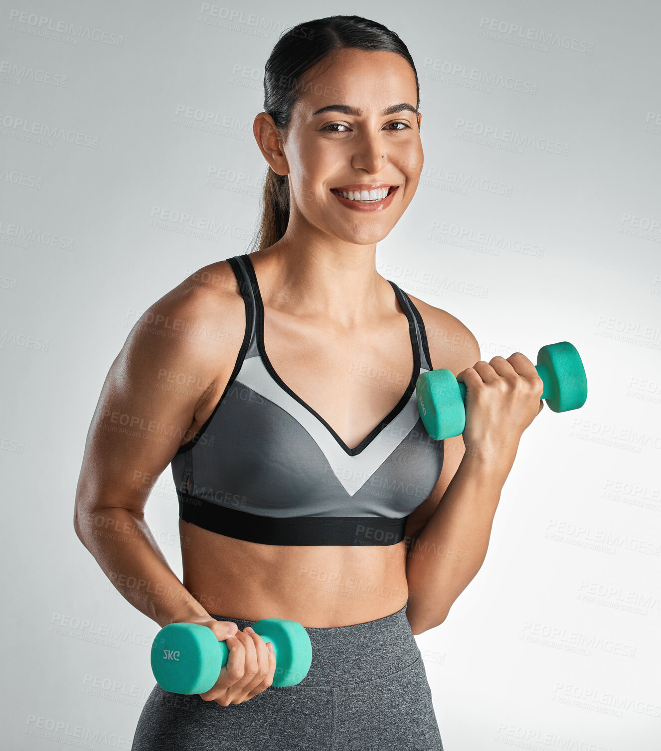 Buy stock photo Studio portrait of a sporty young woman exercising with dumbbells against a grey a background