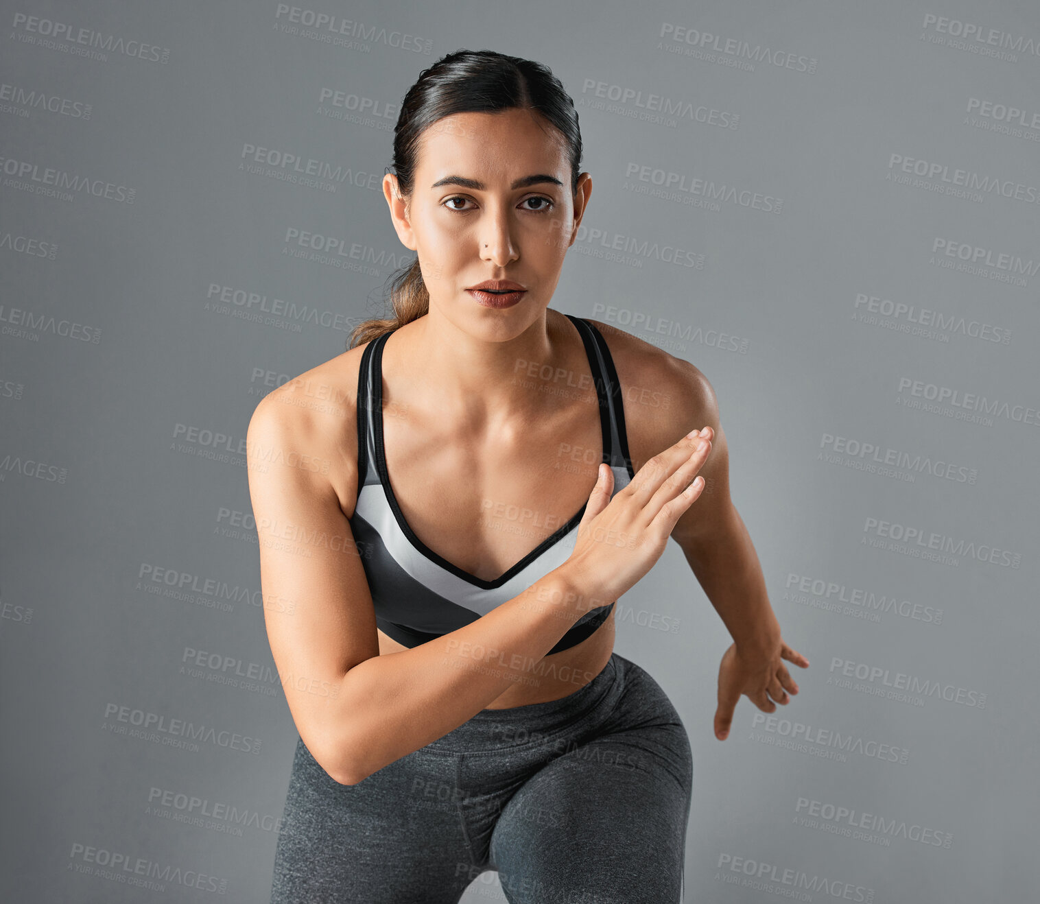 Buy stock photo Studio portrait of a sporty young woman running against a grey background