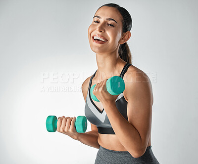 Buy stock photo Studio portrait of a sporty young woman exercising with dumbbells against a grey a background