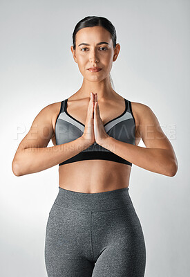 Buy stock photo Studio portrait of a sporty young woman meditating against a grey background