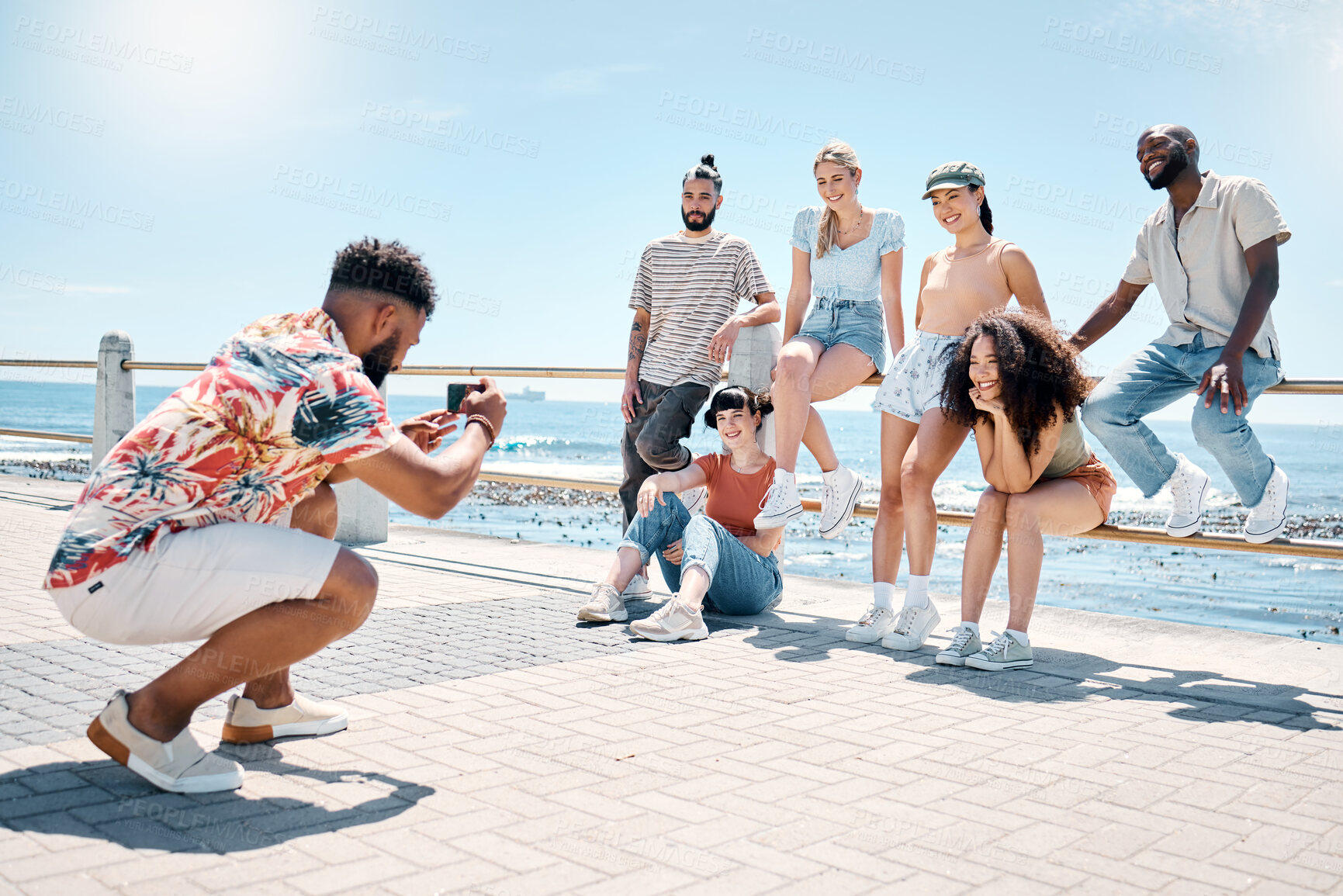 Buy stock photo Full length shot of a young man using his cellphone to photograph his friends during a day outdoors