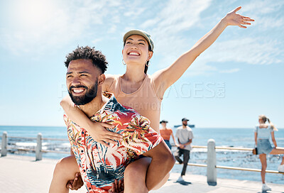 Buy stock photo Shot of a handsome young man giving his girlfriend a piggyback ride during a day outdoors