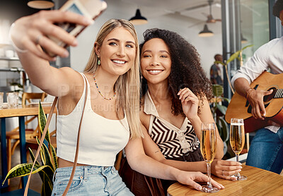 Buy stock photo Shot of two friends taking selfies together at a cafe