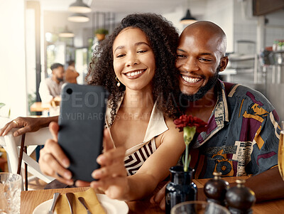 Buy stock photo Shot of a young couple on a date at a restaurant taking selfies using a cellphone