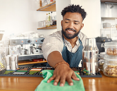 Buy stock photo Shot of a young waiter wiping down the counters in his restaurant