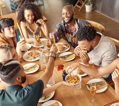 Buy stock photo Shot of a group of young friends enjoying a meal together at a restaurant