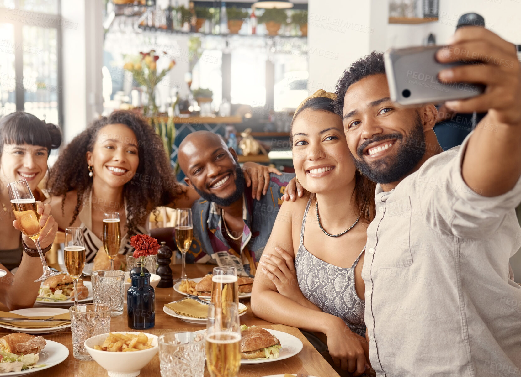 Buy stock photo Shot of a group of young friends taking selfies together at a restaurant