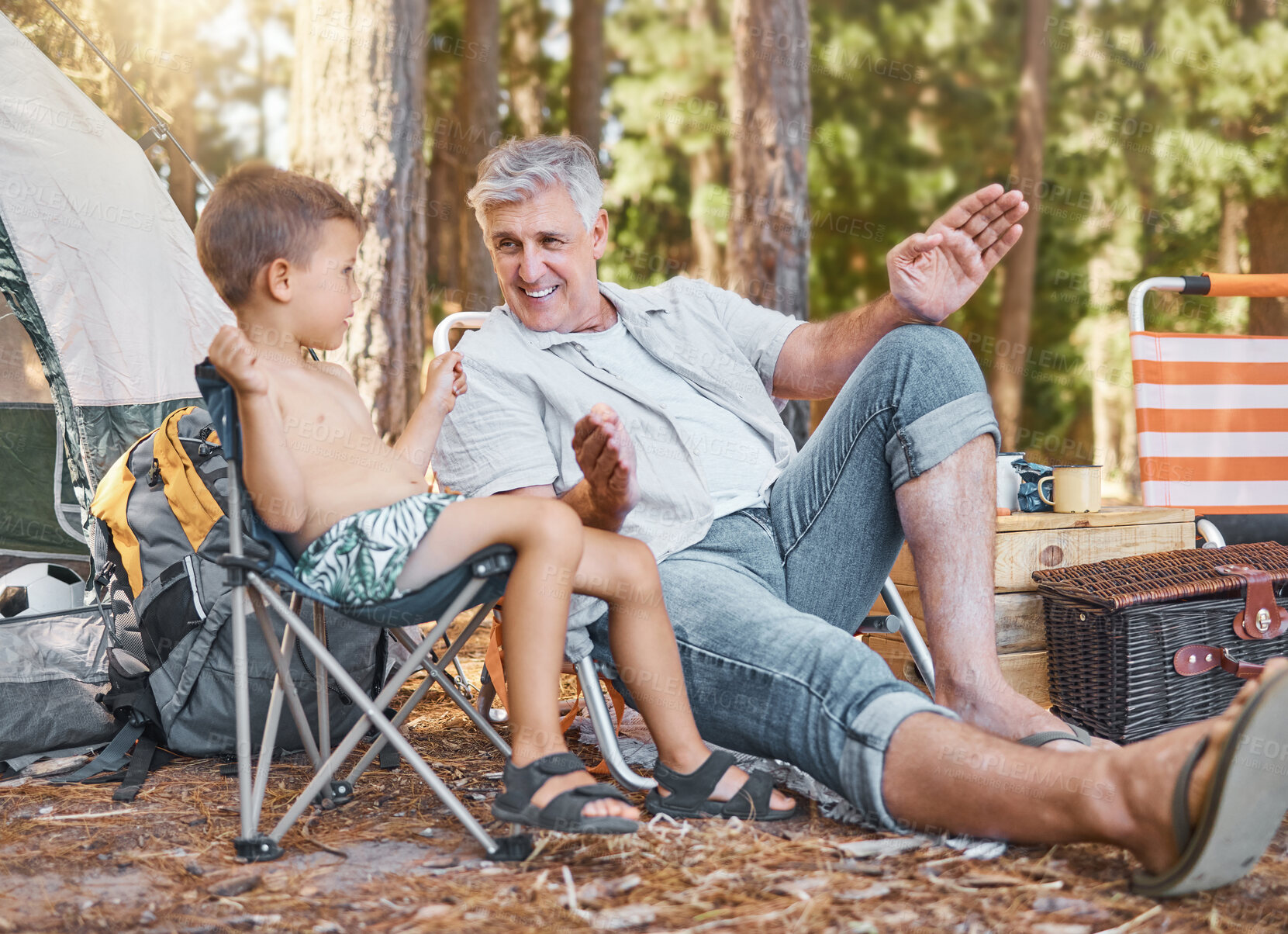 Buy stock photo Child, senior man and camping outdoor in nature with a smile, fun and family travel for summer holiday. Happy grandpa and kid camper talking at a camp site, forest or woods with love for adventure