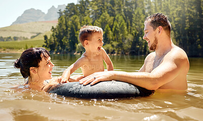 Buy stock photo Family, child floating in tube with parents and swimming in lake with happiness in nature on summer vacation. Energy, adventure and fun outdoor, people in water with laughter, travel and holiday