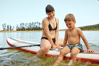 Buy stock photo Lake, mother and son on paddle board, relax outdoor with summer holiday and travel with feet in water. Adventure, freedom and nature, woman and boy child in swimsuit, vacation and bonding together
