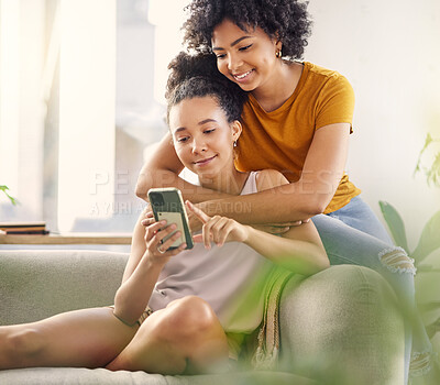 Buy stock photo African lesbian couple, sofa and phone with texting, social network app and relax with meme in living room. Women, together and smartphone for chat, contact or watch internet video on lounge couch