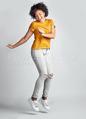 Buy stock photo Jump, excited and young woman celebrating success with smile or motion for freedom and happiness on grey studio background. Energy, winner and jumping for success or joy in the air for achievement 