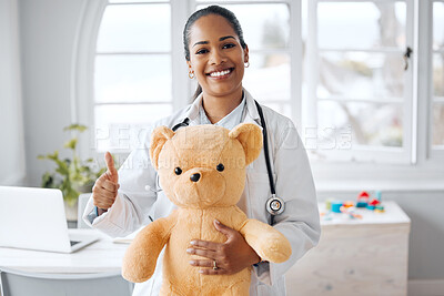 Buy stock photo Shot of a female pediatrician holding a teddy bear while giving the thumbs up