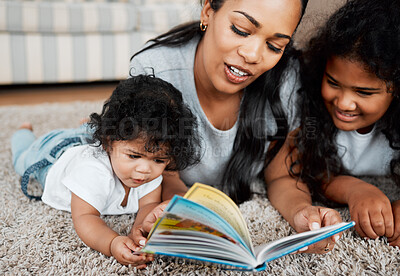 Buy stock photo Happy mom, kids and reading with book on floor for story, bonding or childhood development at home. Mother, baby and child with novel or storytelling for learning, education or fairy tale at house